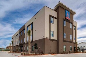 A modern hotel building with a flat roof, multiple windows, and a sign indicating it is a 6-star hotel. - 2 Queen Beds | Non-Smoking, Kitchen (Katy)
