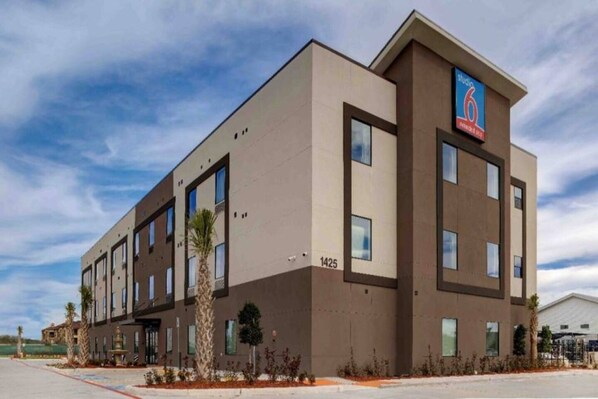 A modern hotel building with a flat roof, multiple windows, and a sign indicating it is a 6-star hotel. - 2 Queen Beds | Non-Smoking, Kitchen (Katy)