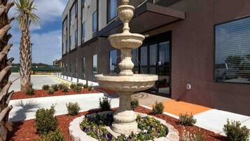 A modern building with a central fountain surrounded by a landscaped garden.