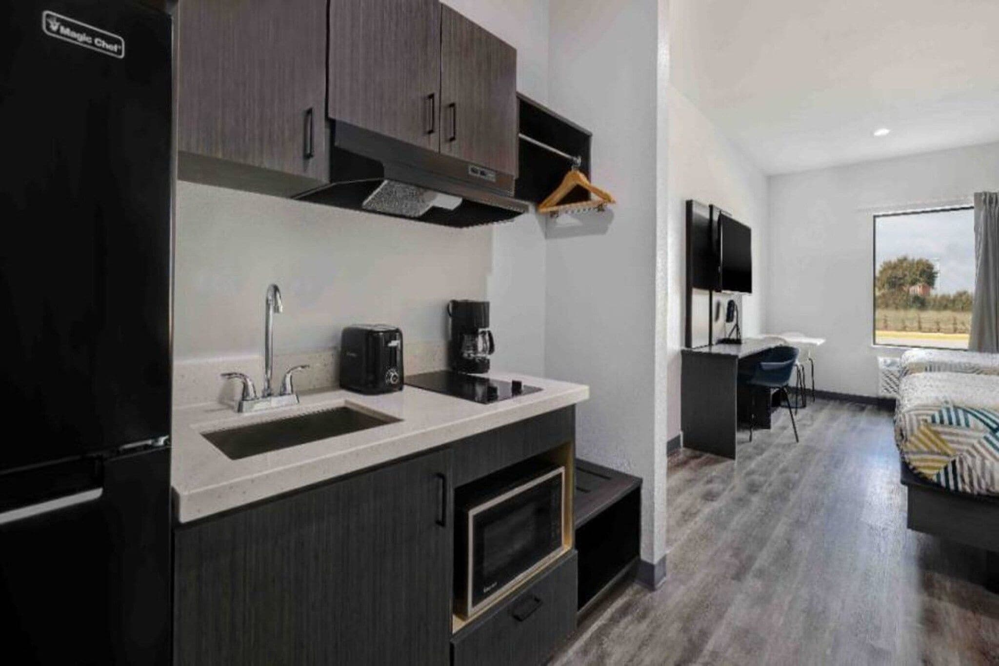 A compact kitchen with a refrigerator, sink, and a coffee maker.