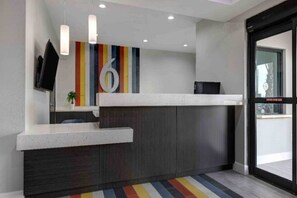 A reception area with a modern design, including a reception desk, a flat-screen TV, and a colorful striped wall. - 2 Beds | Hearing Accessible, Kitchen (Katy)
