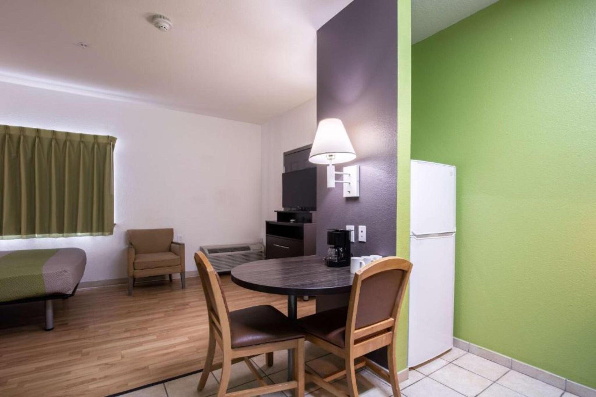 Una habitación compacta con una mesa de comedor, sillas, un sofá, un televisor y un refrigerador.