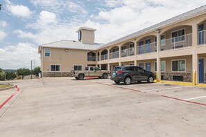A multi-story hotel with a parking lot, a stone facade, and a flat roof.