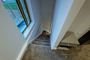 Una escalera alfombrada con una ventana a la izquierda.