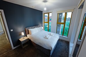 Ein Schlafzimmer mit Bett, Nachttisch und zwei Fenstern.