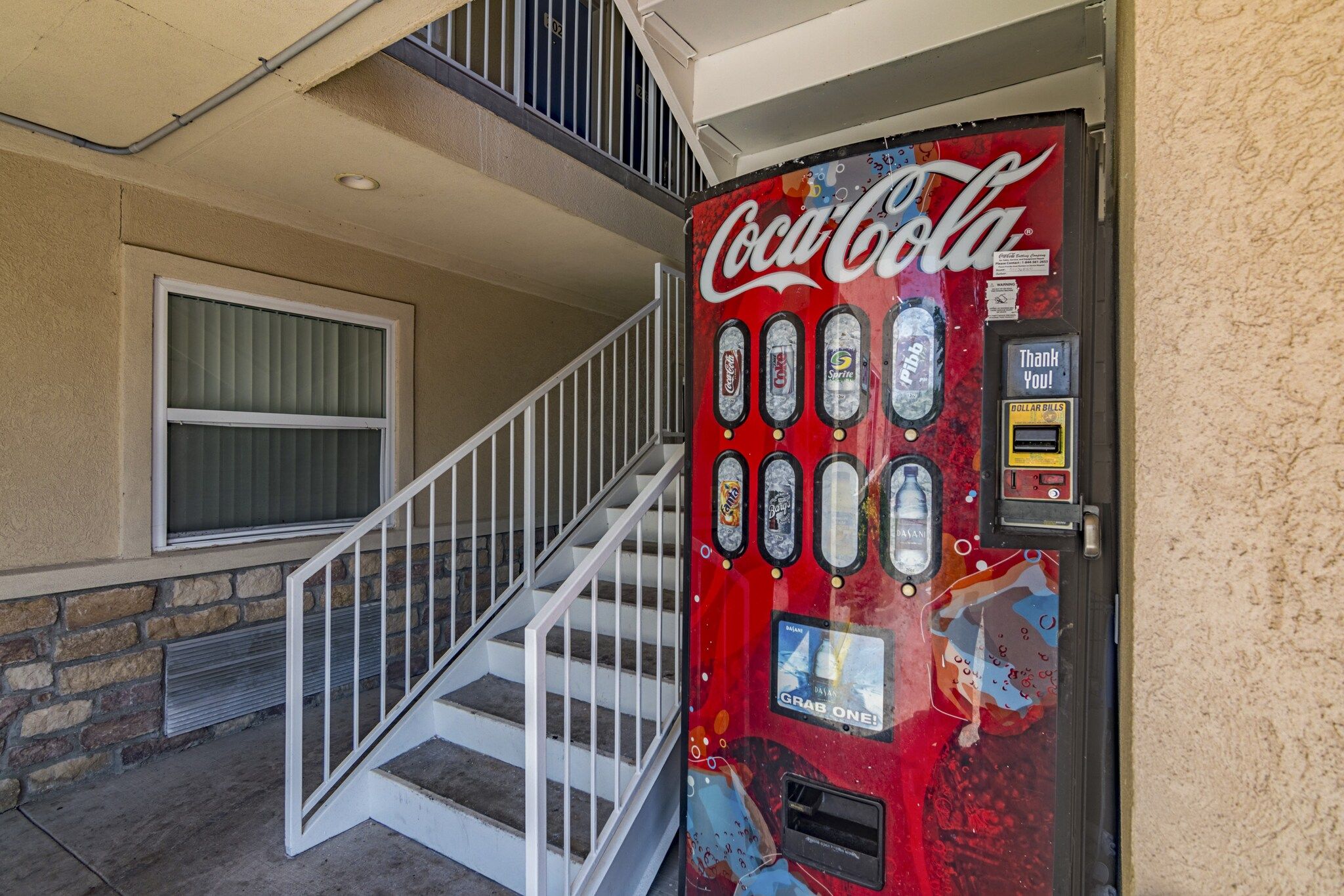 A Coca-Cola vending machine with a 'Thank You!' sign and a 'Dollar Bills' slot.