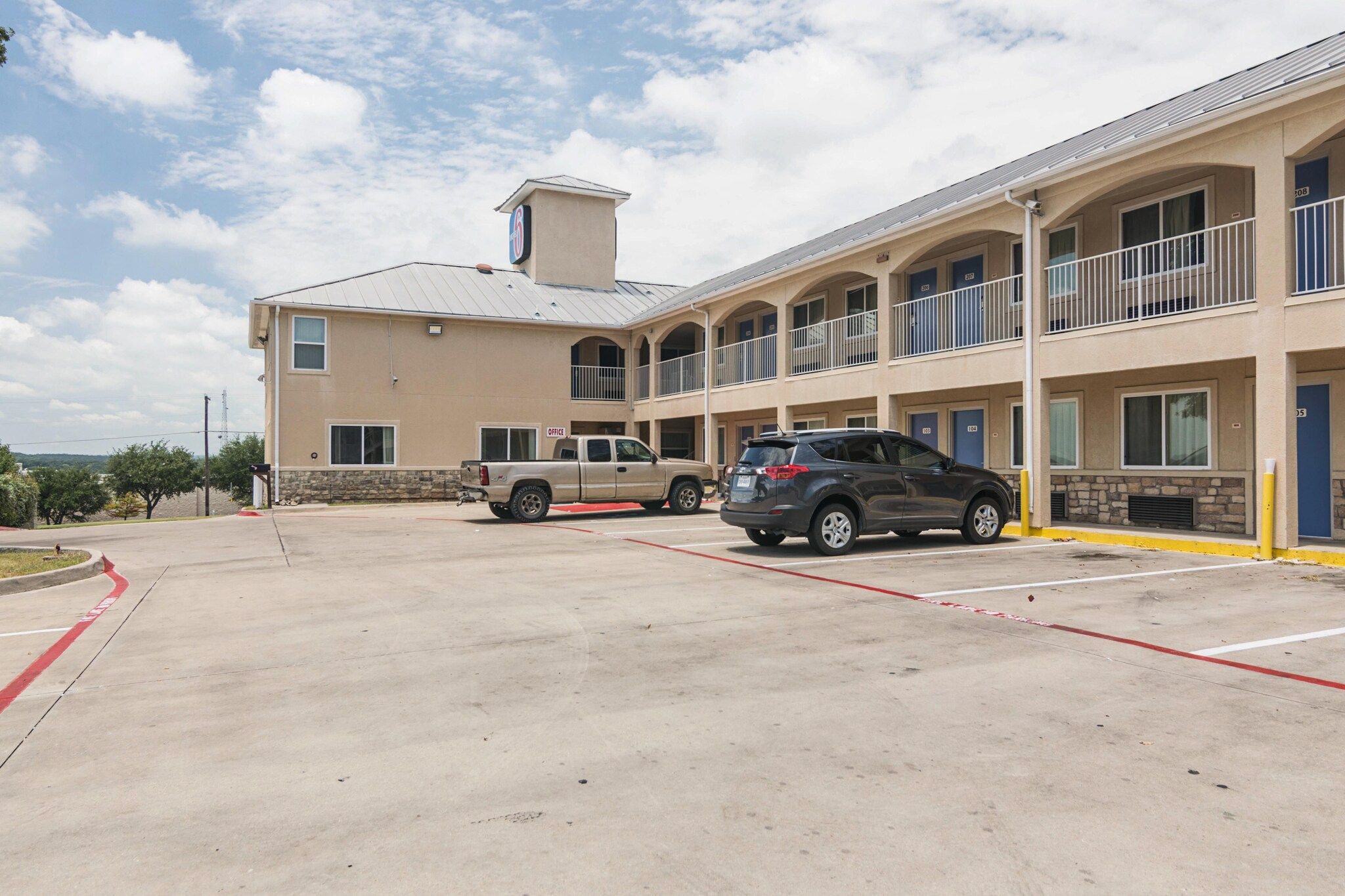A multi-story hotel with a parking lot, a stone facade, and a flat roof.