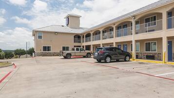A multi-story hotel with a parking lot, a stone facade, and a flat roof.