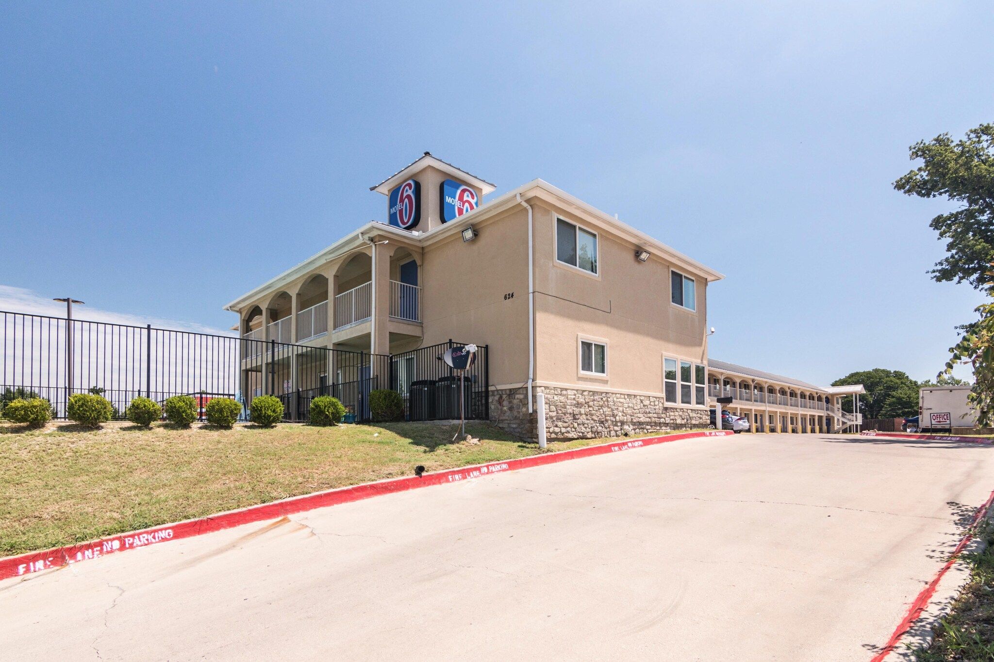 A motel with a two-story structure, a stone base, and a flat roof.