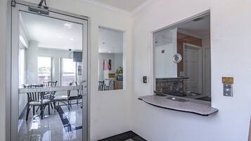 A hallway with a glass door leading to a dining area, a wall-mounted mirror, and a sign indicating a service bell.