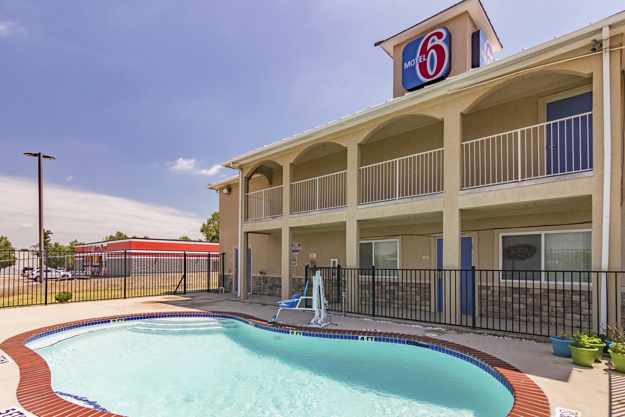 Un motel doté d’une piscine, d’un espace extérieur aménagé et d’un panneau indiquant le numéro 6.