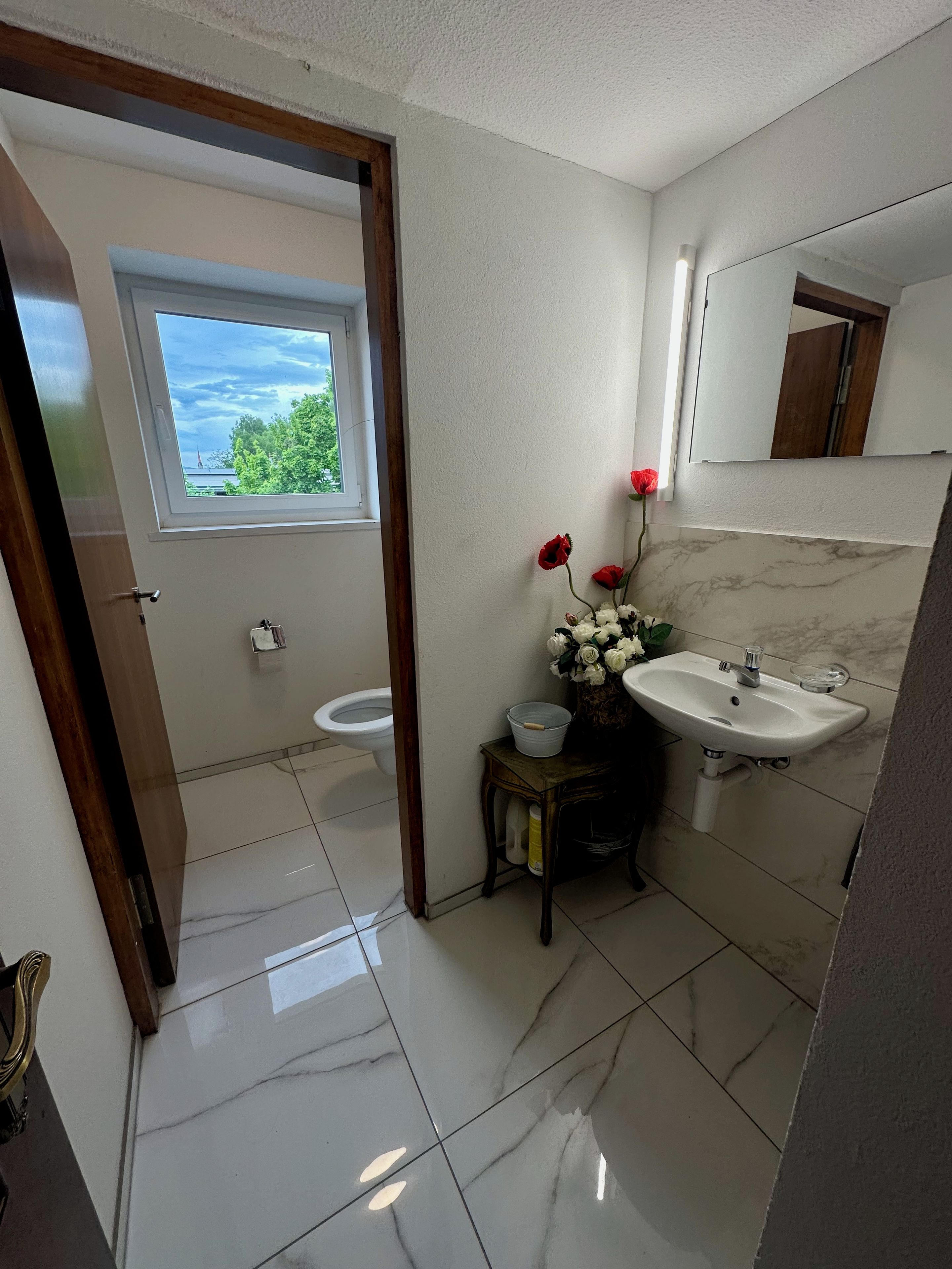 Une salle de bain avec des toilettes, un lavabo et une fenêtre.