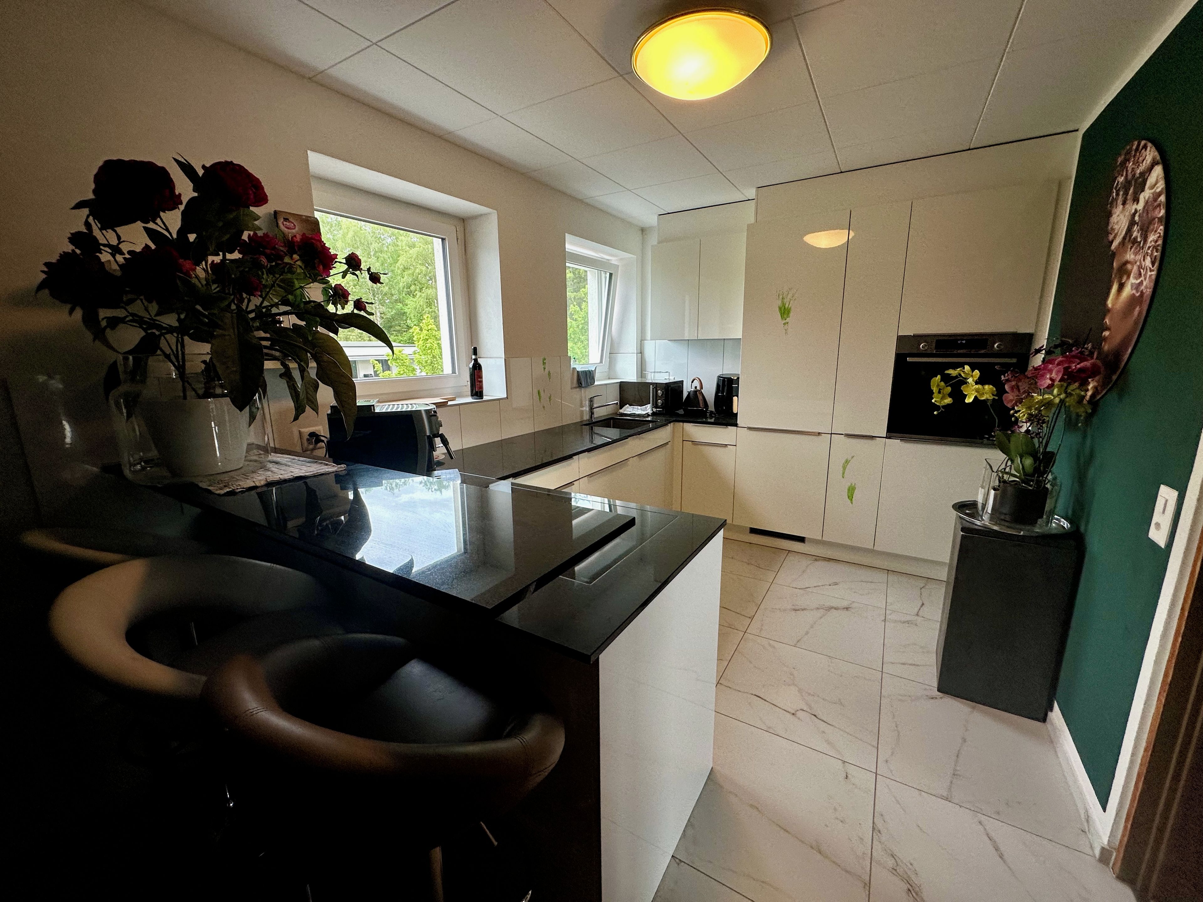 Una cocina moderna con una isla central, muebles blancos y una pared de acento verde.