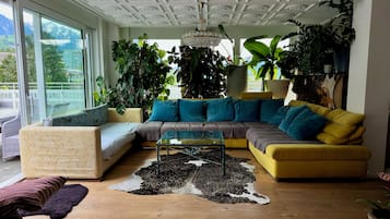 Una sala de estar con un sofá amarillo, una mesa de centro de vidrio y un techo con diseños elaborados.