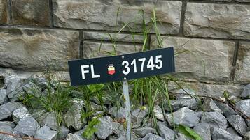 Una señal de calle con el texto 'FL 31745' sobre un fondo de pared de piedra.