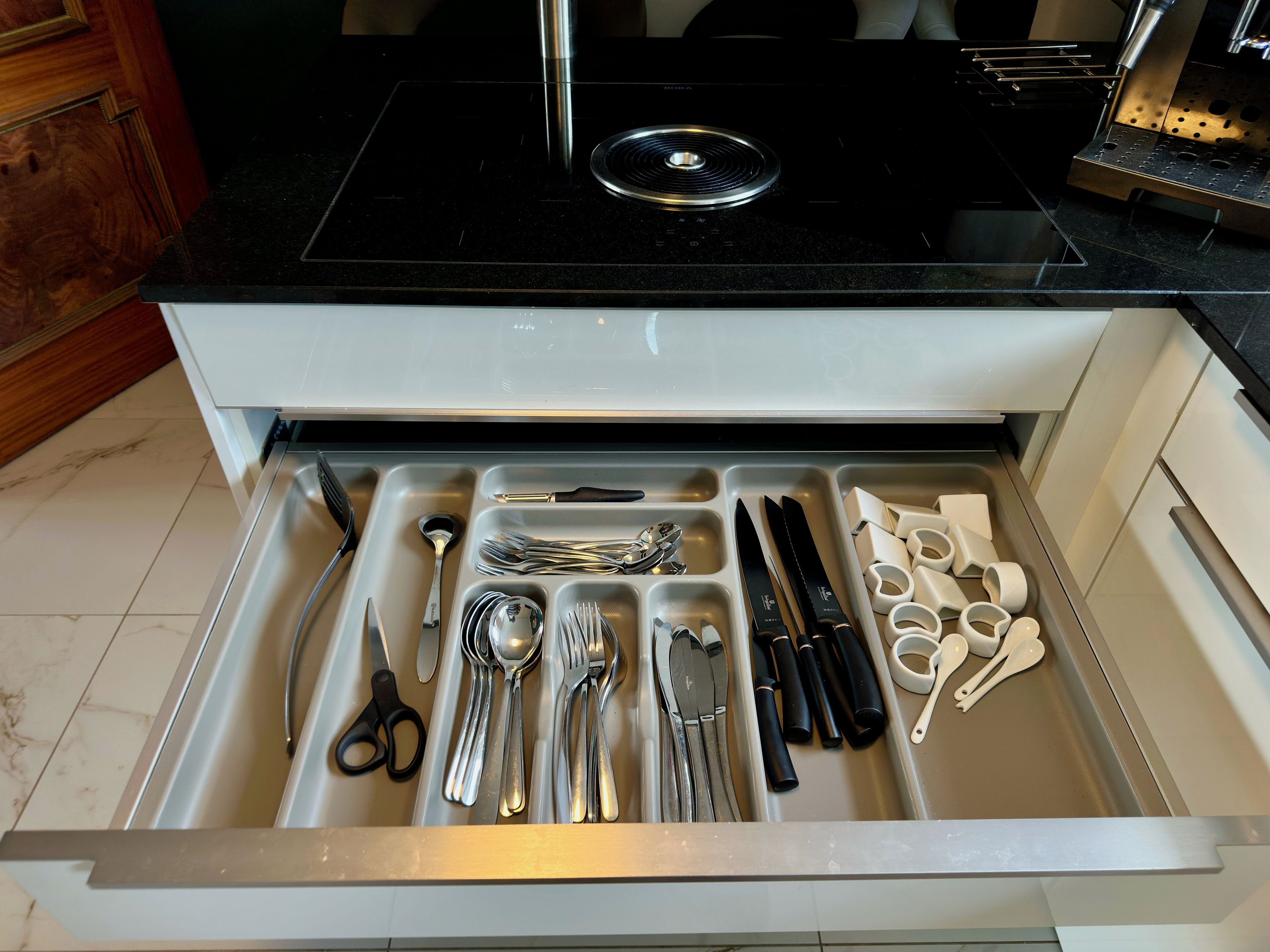 A kitchen drawer with utensils and a black stovetop.