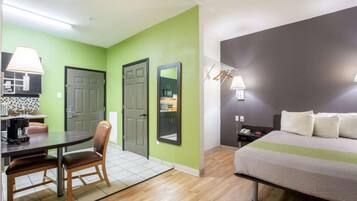 Quarto de hotel com área de jantar, cama e cozinha compacta.