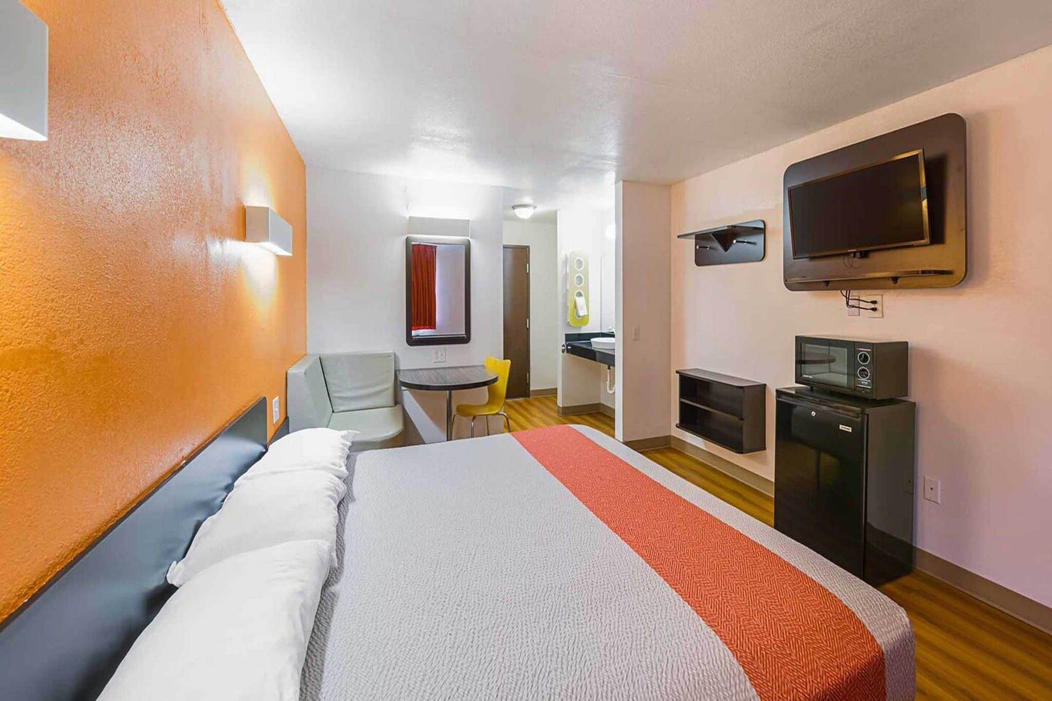 Een hotelkamer met een bed, een bureau, een stoel, een televisie en een magnetron.