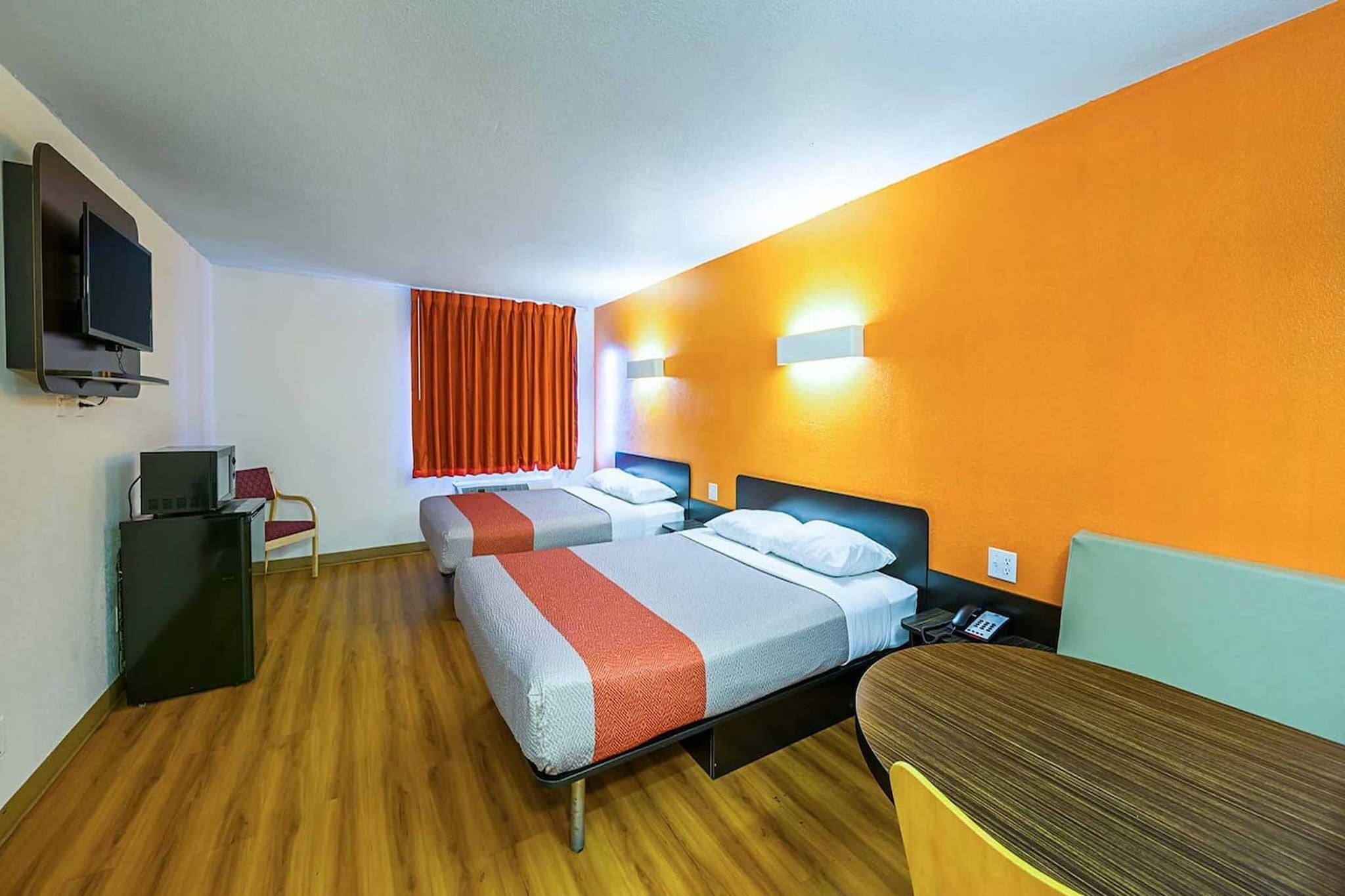 Une chambre d’hôtel avec deux lits, un bureau, une télévision et une armoire.