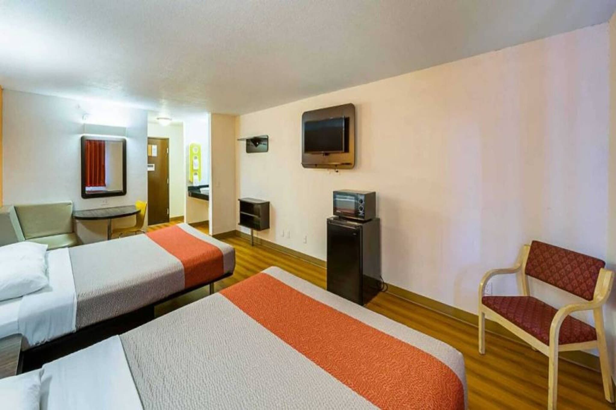 Une chambre d’hôtel avec deux lits, un bureau, une chaise, une télévision et un petit réfrigérateur.