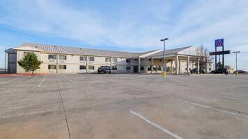 A motel with a large parking lot, a gas station, and a sign for a 6-star hotel.