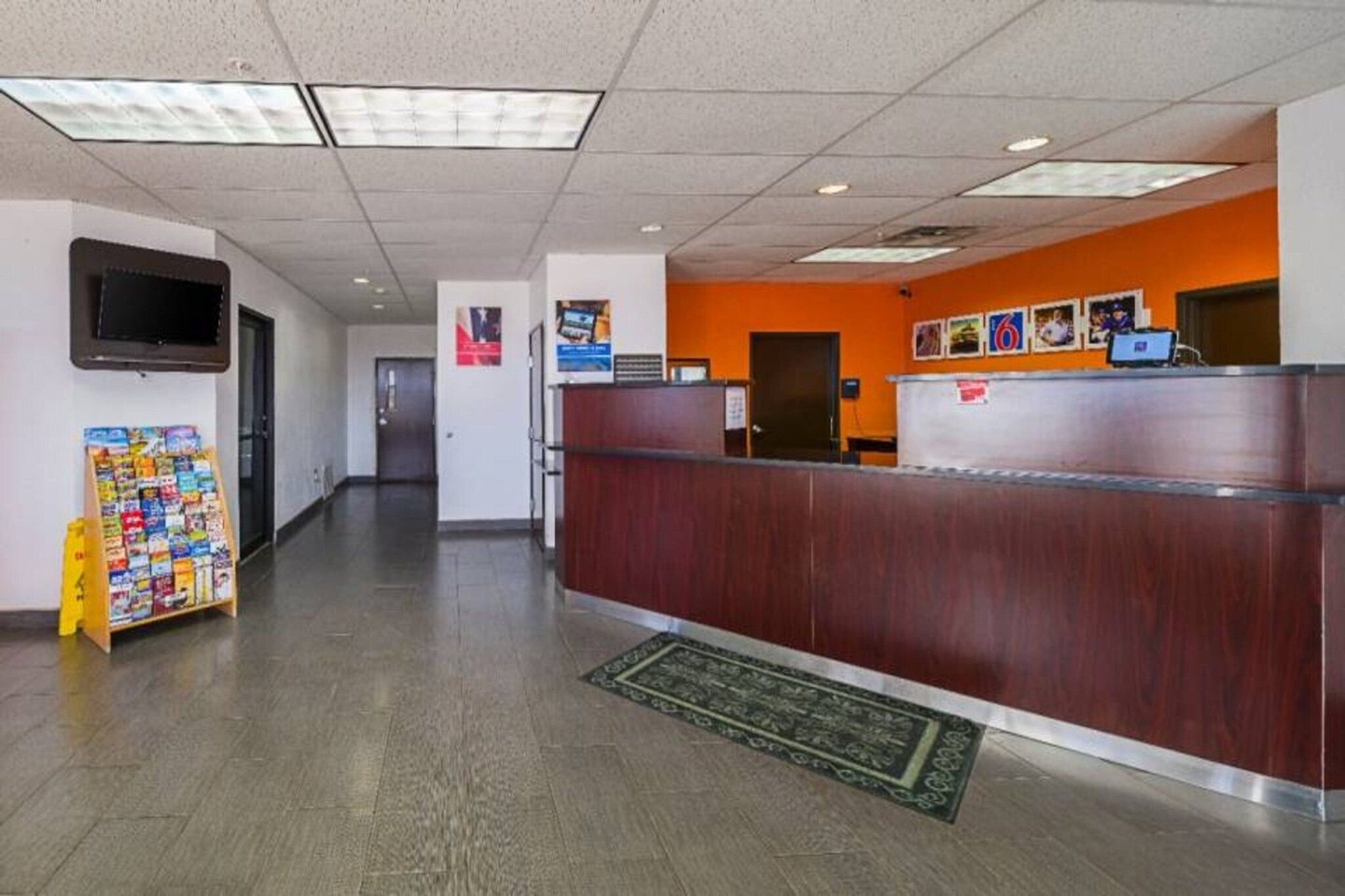 A reception area with a counter, a television mounted on the wall, and a magazine rack.