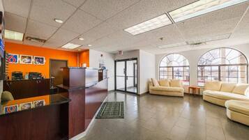 A reception area with a counter, a seating area with couches, and large windows.
