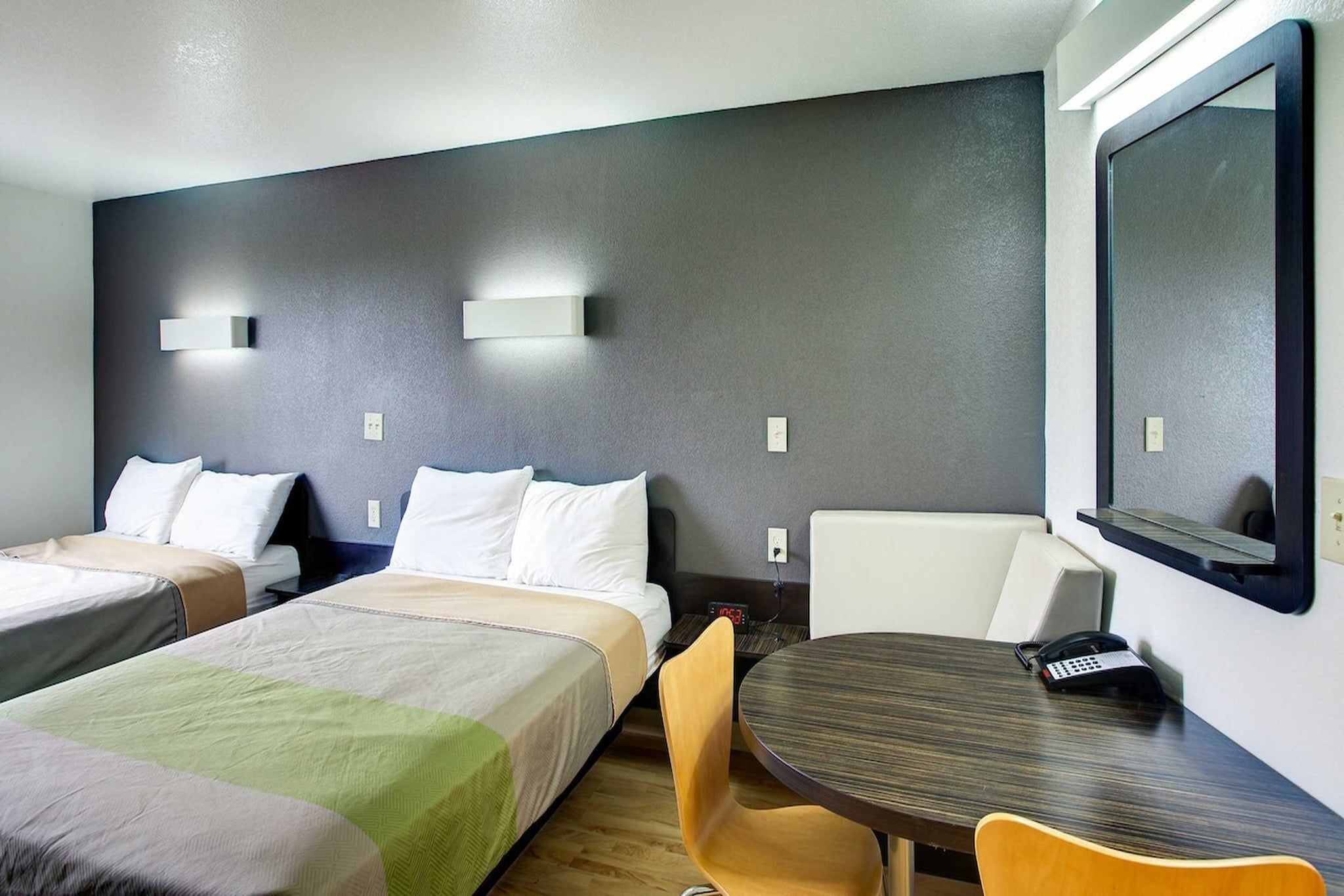 Een hotelkamer met twee bedden, een bureau, een stoel, een televisie en een klok.