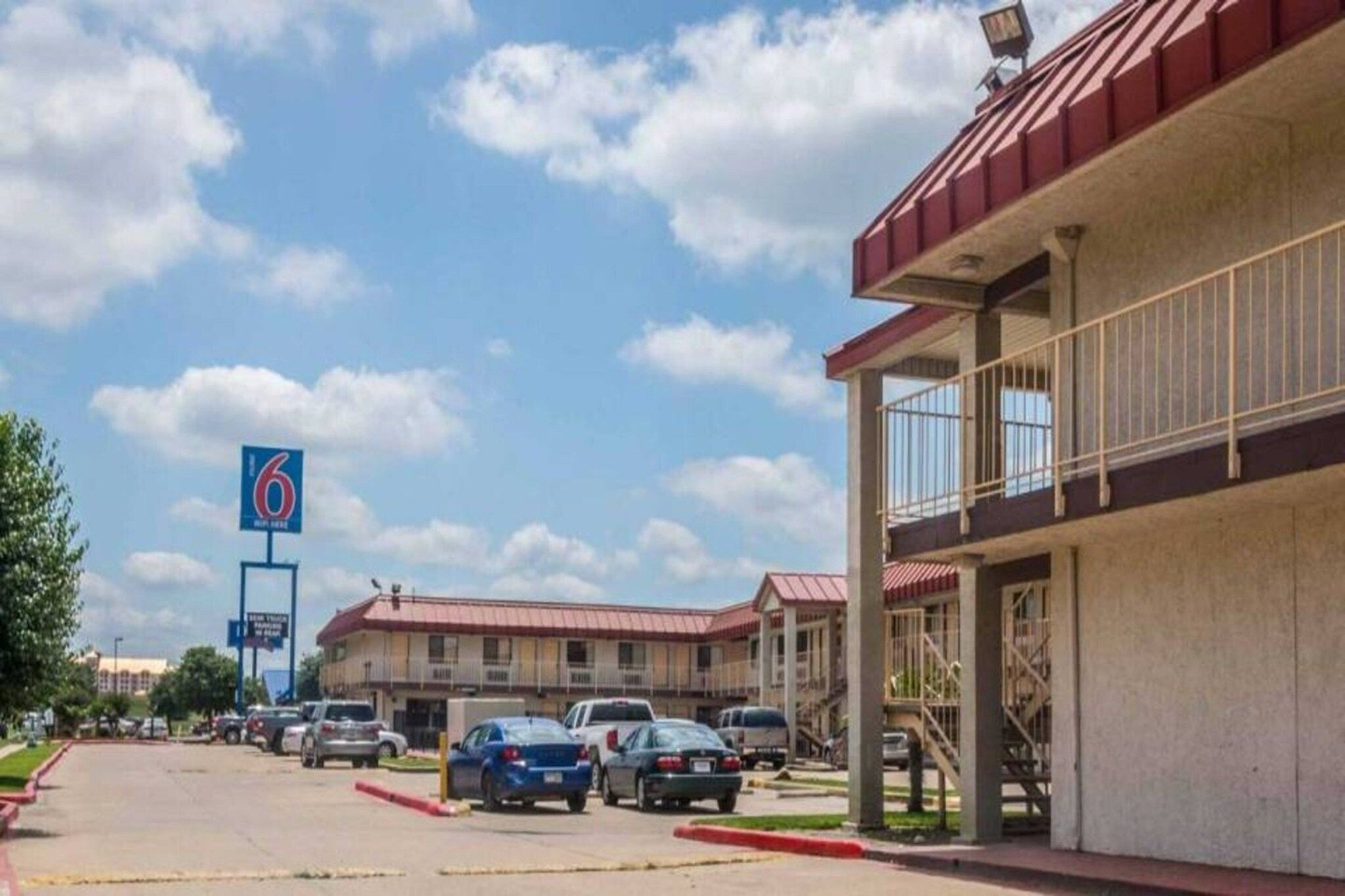A motel with multiple parking spaces and a large sign indicating the name.