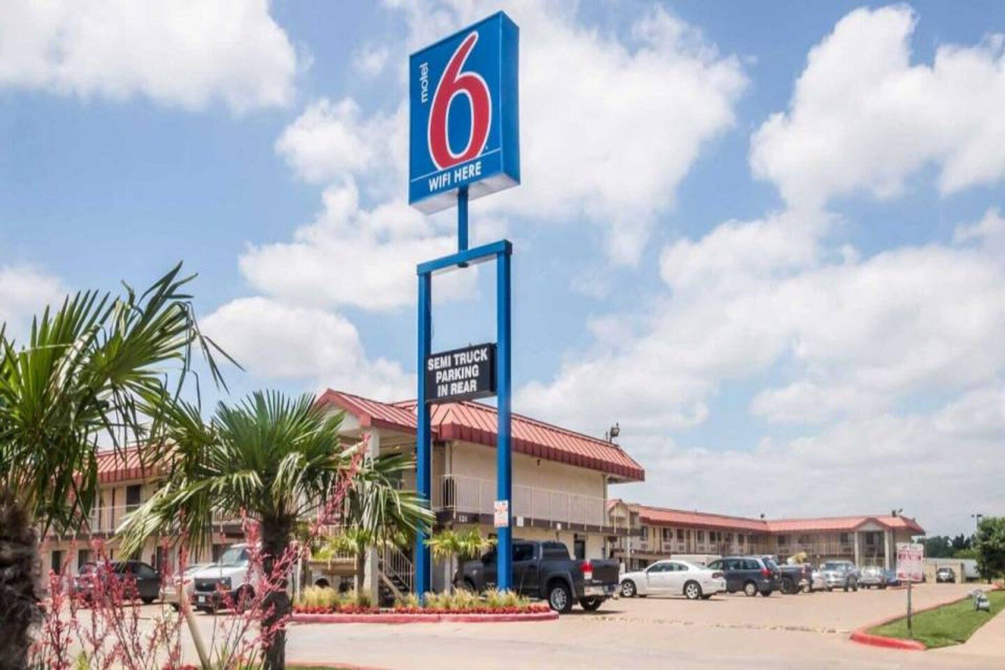 A motel with a sign indicating WiFi availability and a semi-truck parking area.