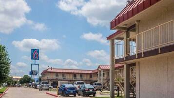 A motel with multiple parking spaces and a large sign indicating the name.