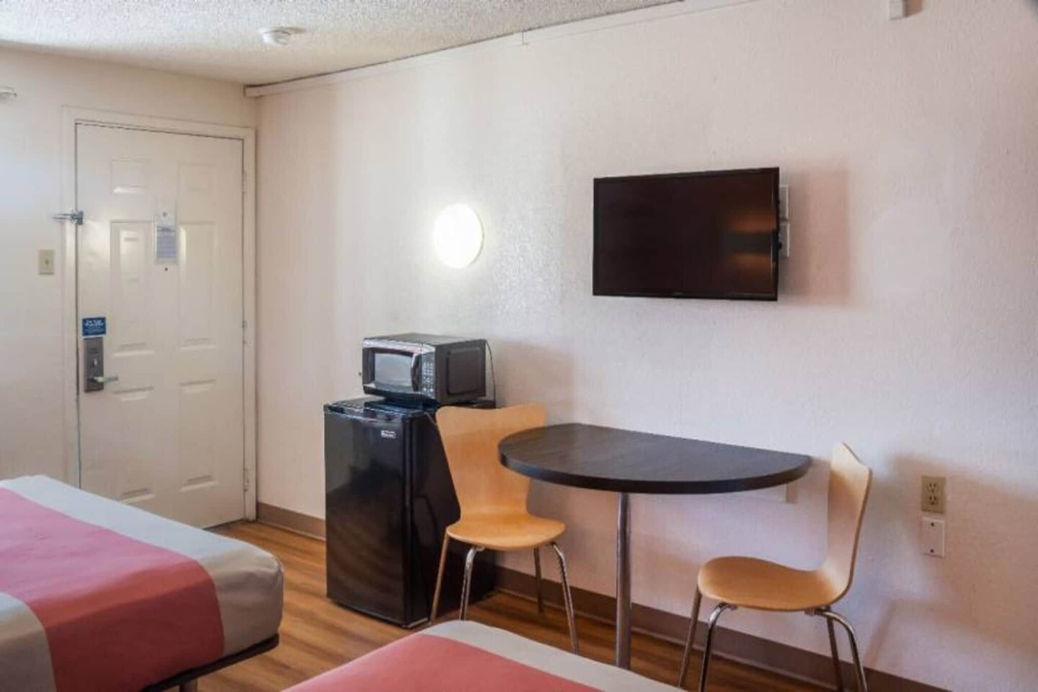 Una habitación de hotel con una cama, un escritorio, una silla, un televisor y un refrigerador.