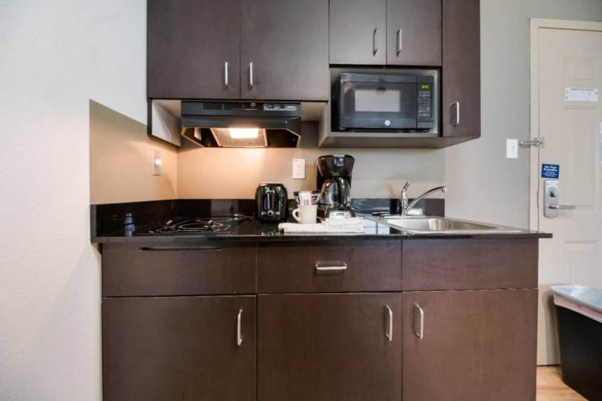 Una cocina compacta con microondas, estufa y cafetera.