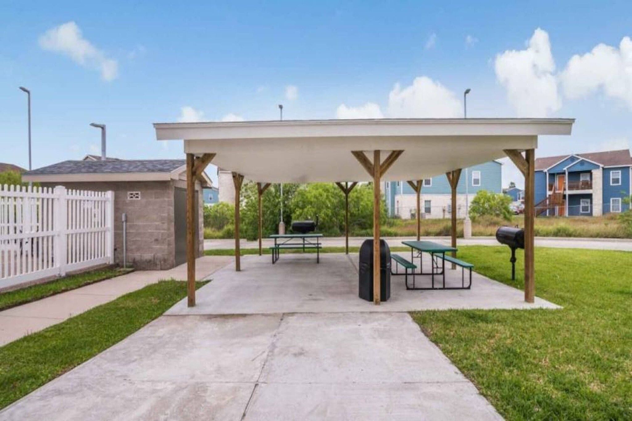A covered outdoor area with picnic tables and a barbecue grill.