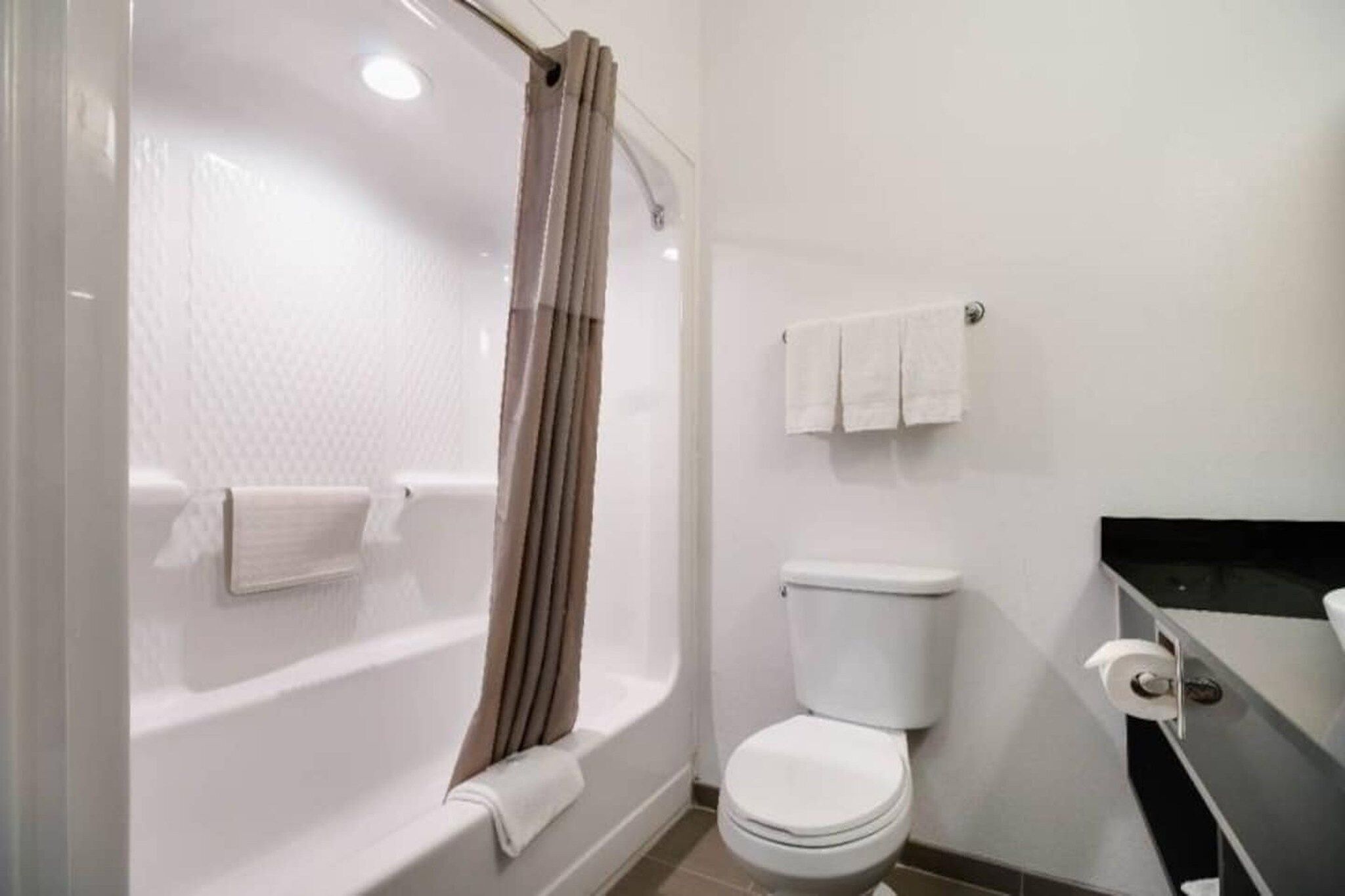 A bathroom with a bathtub, toilet, and a towel rack.