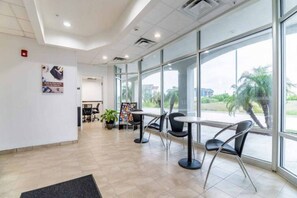 A spacious indoor area with large windows, a reception desk, and several tables with chairs. - Cozy 1 Queen Bed | Nsmk, Kitchen (INGLESIDE)