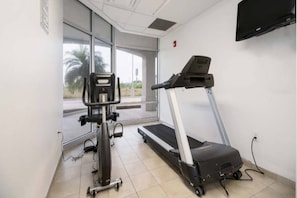 Een fitnessruimte met een loopband, een hometrainer en een gewichtstoestel.