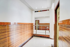 Un pasillo con paredes decoradas, barandilla metálica y una puerta.