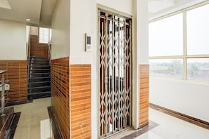 Un pasillo con una escalera, una reja metálica y un ventanal con vistas al exterior.