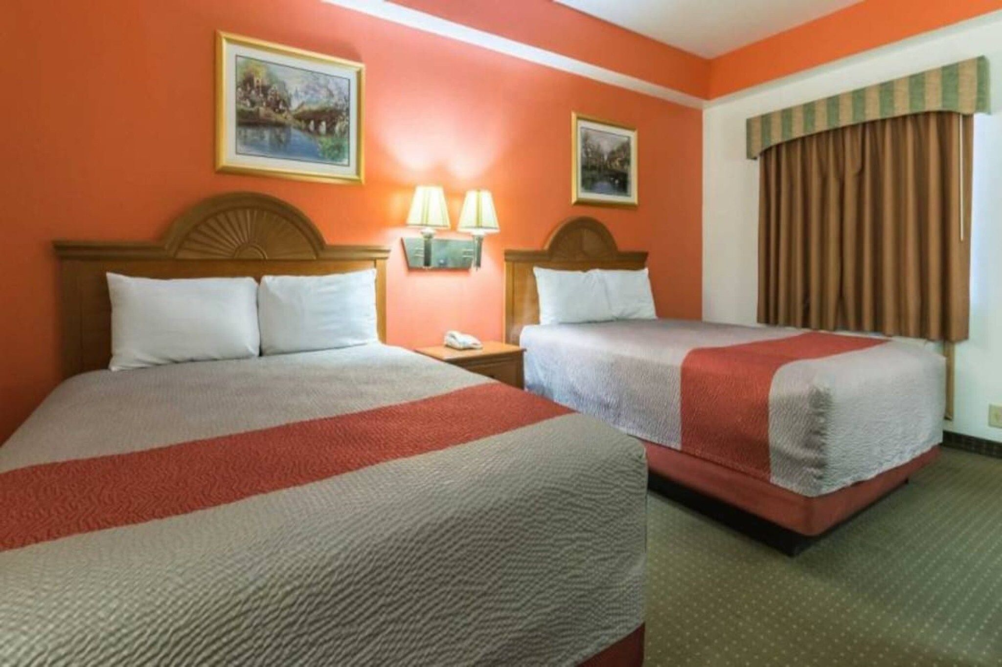 Une chambre d’hôtel avec deux lits, une table de chevet avec des lampes et une fenêtre avec des rideaux.