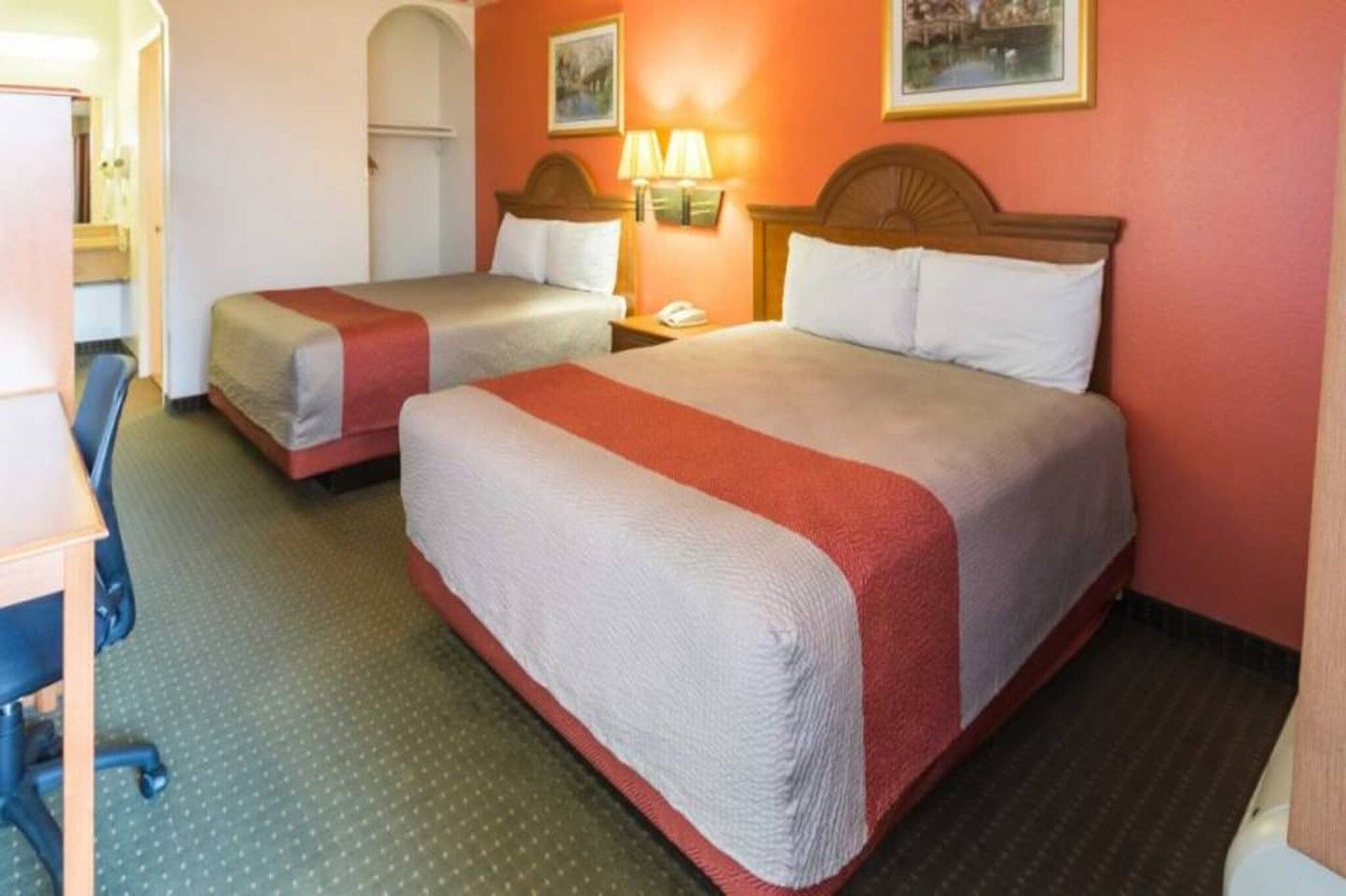 Une chambre d’hôtel avec deux lits, un bureau et une chaise.
