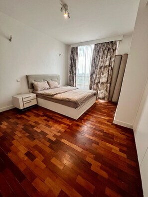 Een slaapkamer met een bed, nachtkastje en een raam met gordijnen.