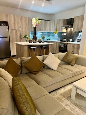 A modern kitchen with a built-in island, wooden cabinets, and a stainless steel refrigerator. - Finewood Residency View Palace Apartment (Nairobi)