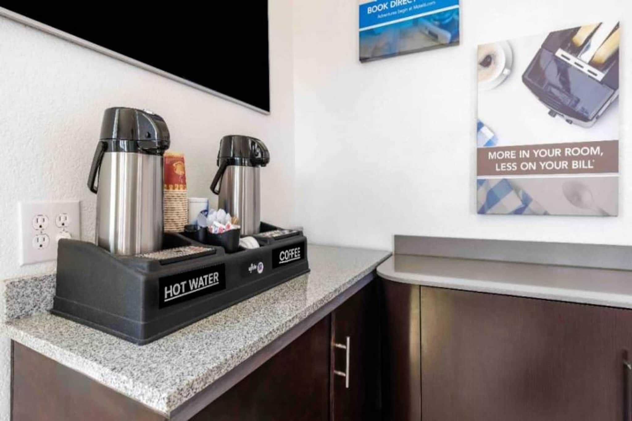 Eine Küchenzeile mit einer Kaffeestation, inklusive zwei Kaffeemaschinen und einem Warmwassergerät.