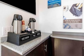 Eine Küchenzeile mit einer Kaffeestation, inklusive zwei Kaffeemaschinen und einem Warmwassergerät.