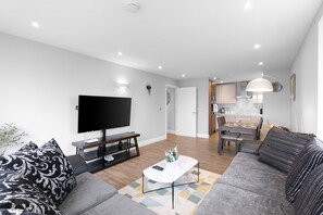 A modern living room with a flat-screen TV, a coffee table, and a sofa. - The Isleworth 2BR 2BA with Gated Parking & Balcony (Isleworth)