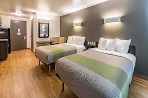 Une chambre d’hôtel avec deux lits, un bureau, un miroir et une porte.