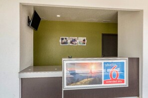 Un espace d’accueil avec un comptoir, un téléviseur fixé au mur et un panneau indiquant « Studio 6 – Séjour prolongé ».