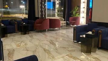 A modern lobby with seating areas, a marble floor, and a glass partition.