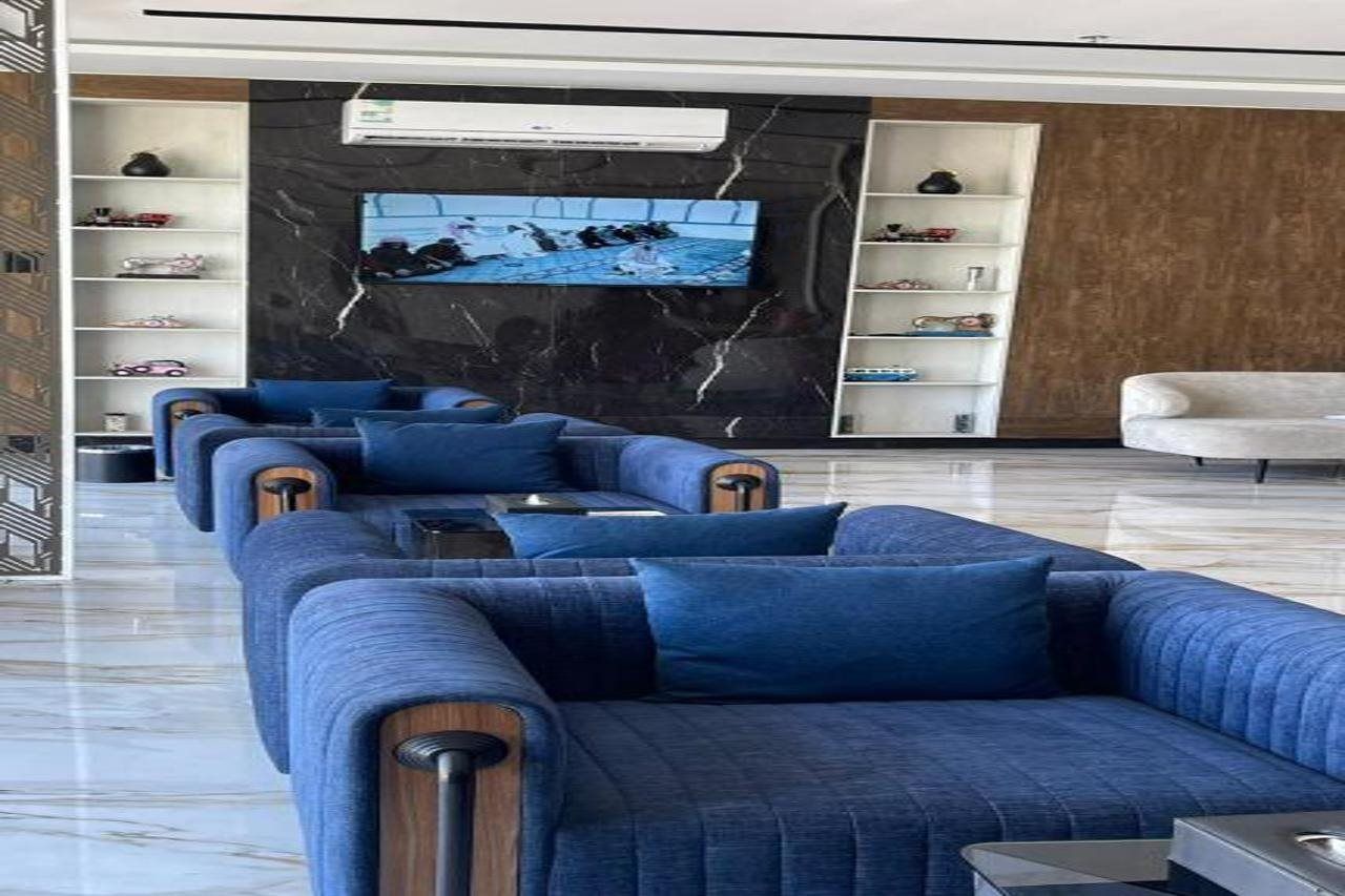 Una sala de estar moderna con un sofá modular, un televisor de pantalla plana montado en una pared de mármol y estanterías empotradas con objetos decorativos.